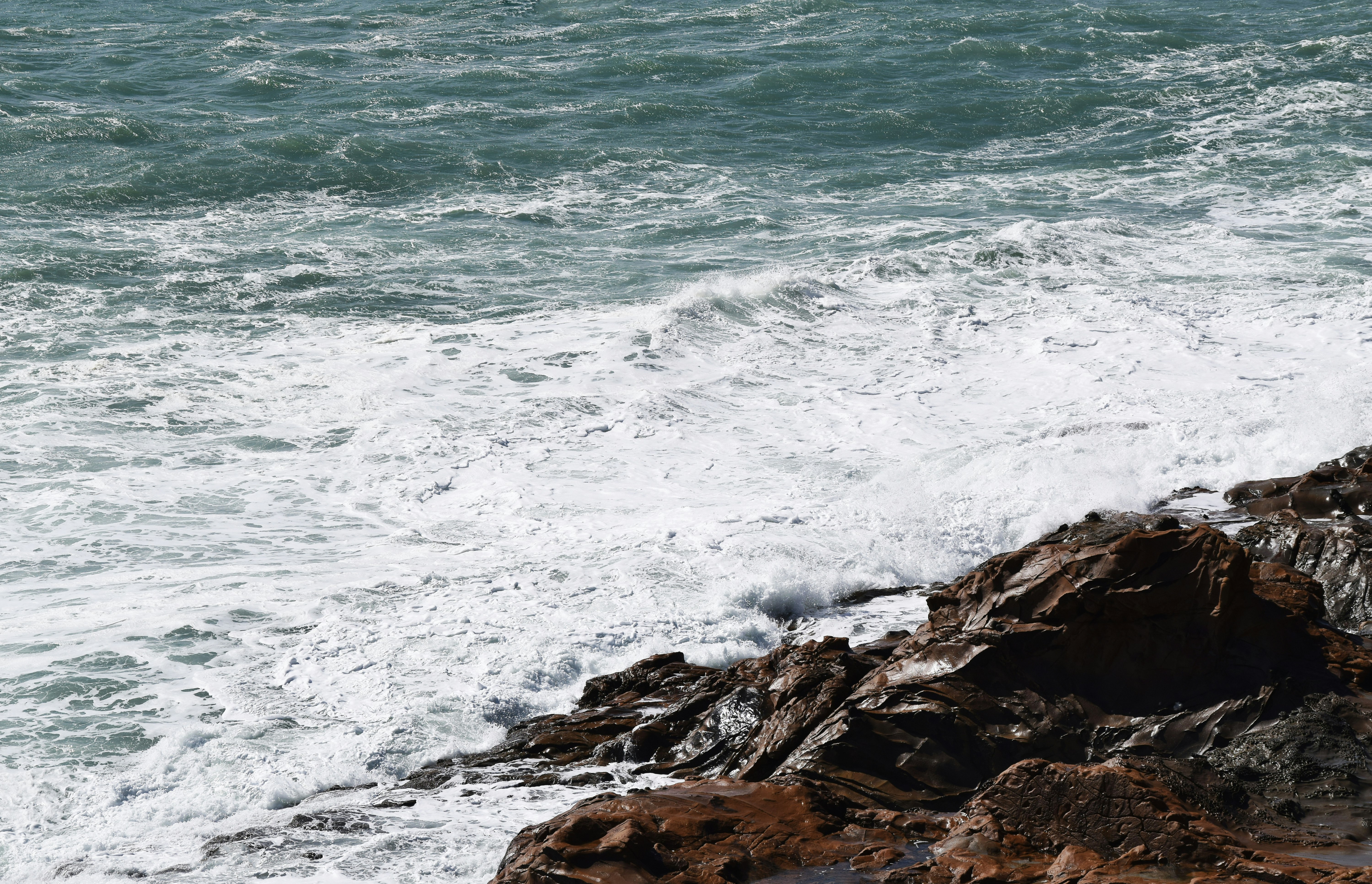 ocean waves crashing on rocky shore during daytime